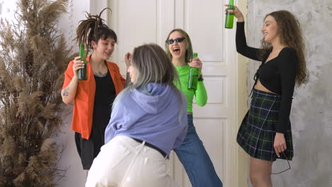 group of four happy girl friends holding beer and dancing during a party at home 1