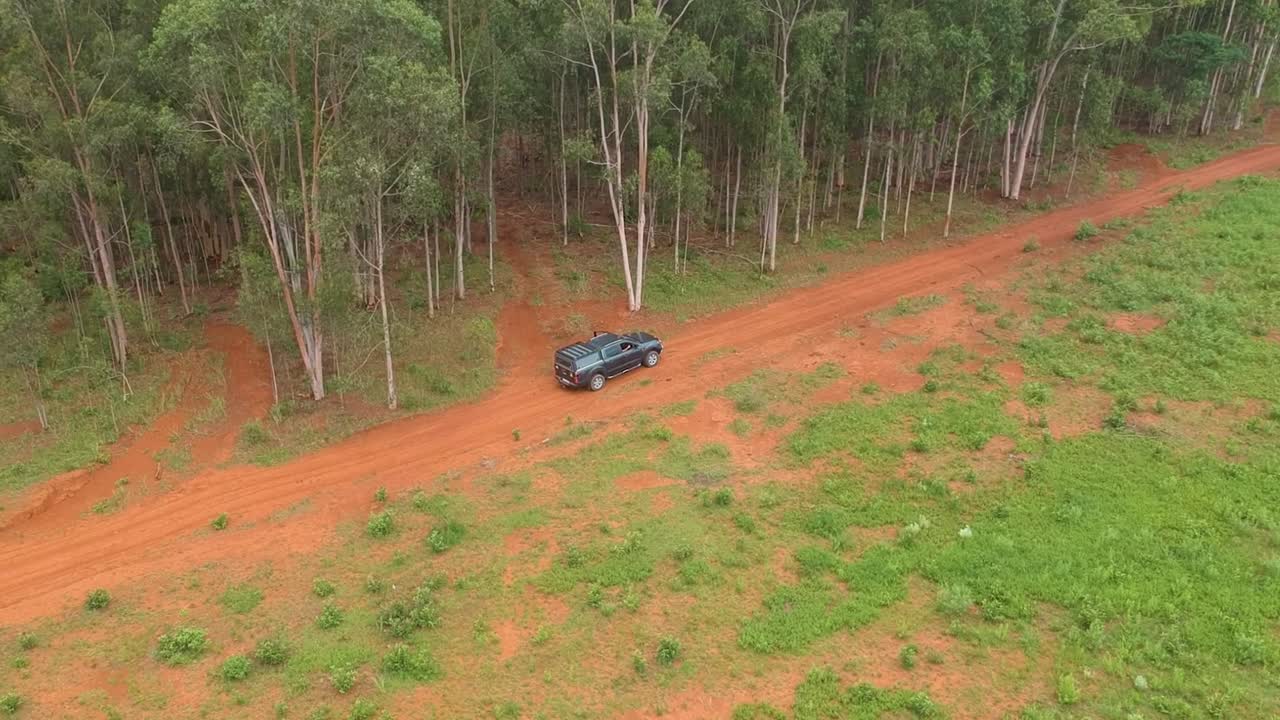 작은 숲 옆 비포장 도로의 픽업트럭, arial follow sho