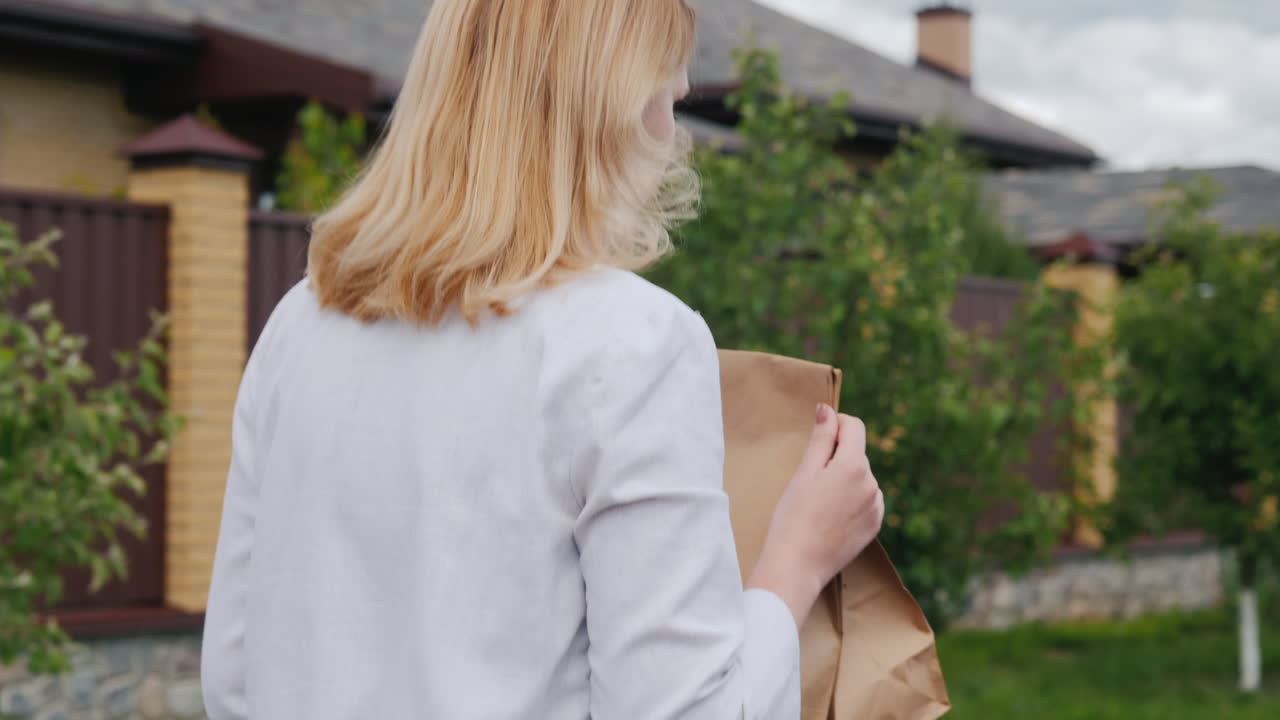 식료품 가방을 들고 집으로 가는 젊은 여성의 뒷모습 1