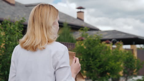 vista trasera de una mujer joven que lleva bolsas de comestibles a su casa 1