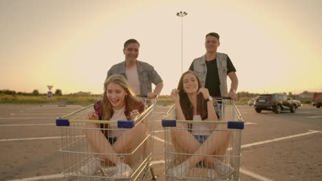 young friends having fun on a shopping carts. multiethnic young people playing with shopping cart