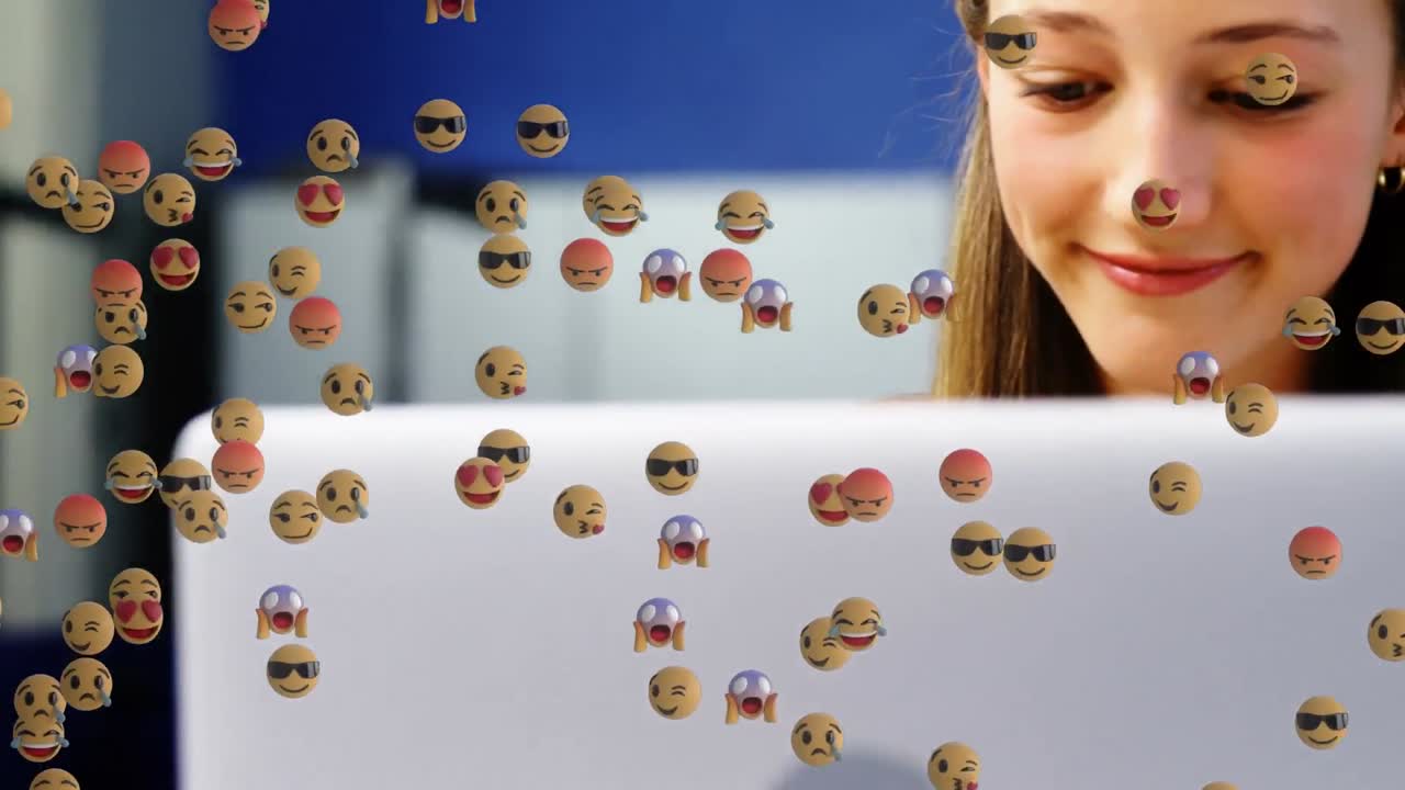 animación de emoticones sobre un niño y una niña caucásicos felices usando computadoras portátiles