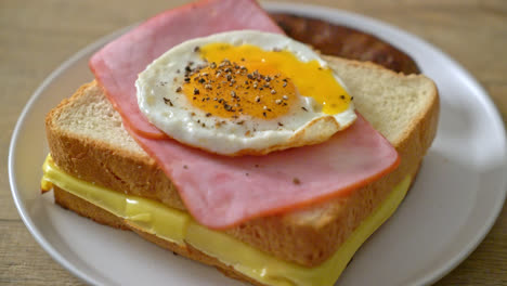 homemade bread toasted cheese topped ham and fried egg with pork sausage for breakfast