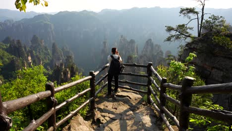 photographer man taking pictures of imperial writing brush peak mountains at sunset from a viewpoint