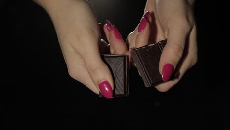 la mujer rompe una barra de chocolate negro. primer plano. cámara lenta.