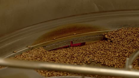 Industrial-coffee-roaster-spin-and-mix-fresh-coffee-beans,-close-up-static-shot