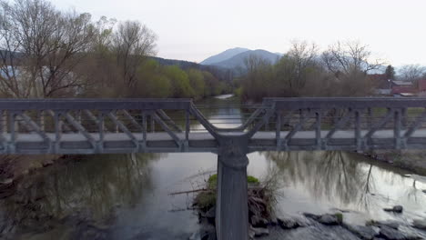 drone shot over a bridge and a river with mountains, 4k uhd