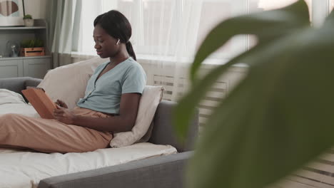 young african woman using digital tablet in bed