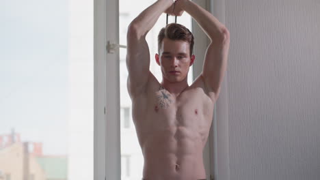 focused teenager trains by pulling resistance rope from behind, shirtless and determined, building strength and flexibility indoors with soft light filtering through window