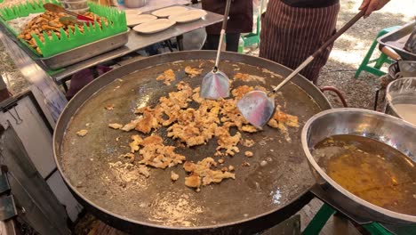 vendor frying and serving crispy snacks outdoors.