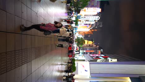 bustling city street at night with pedestrians and neon lights