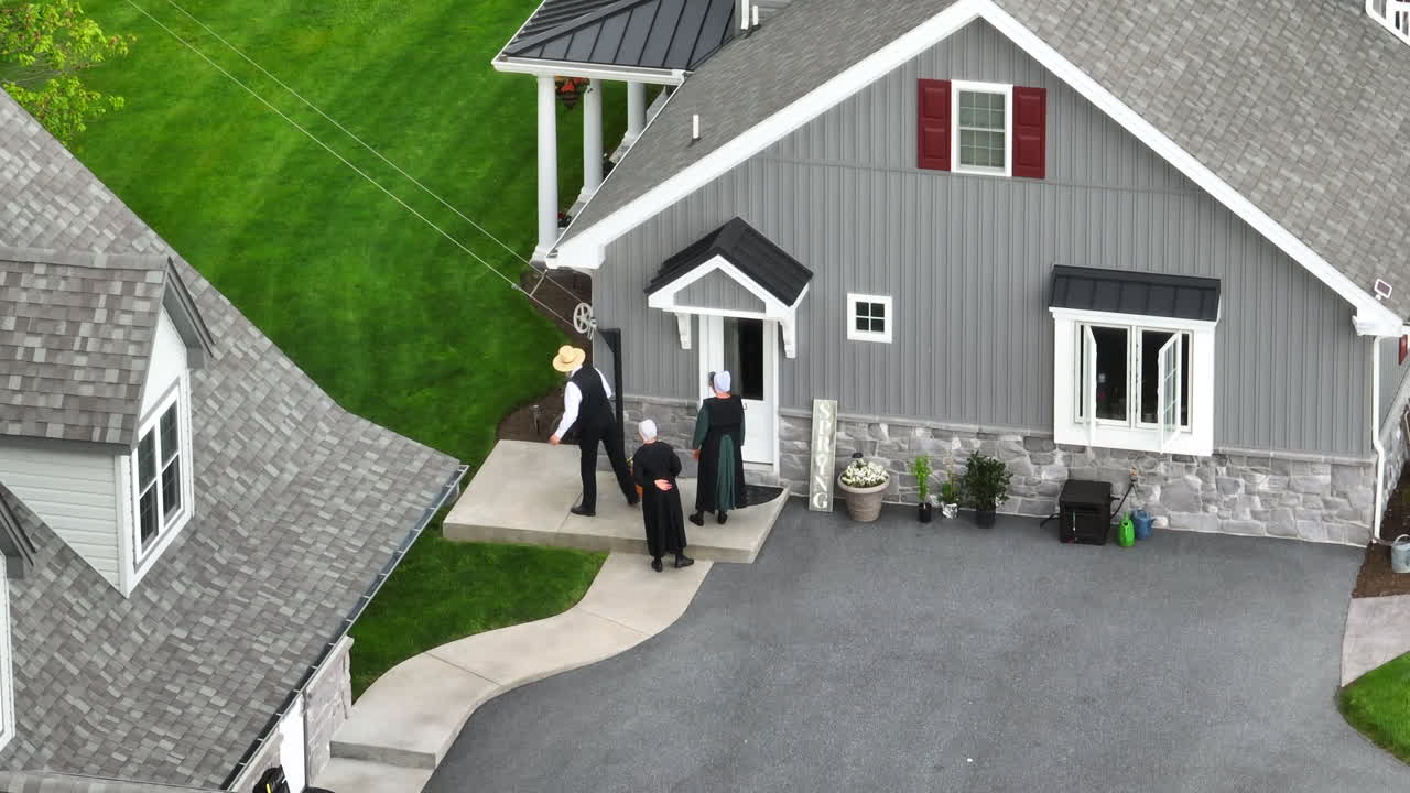 Amish people entering home. Aerial zoomed view of old fashioned Lancaster, PA Amish. Amish home with washline on spring day in America. Amish farm dog runs into house.