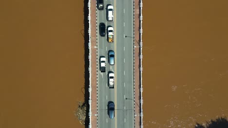 top down aerial drone shot over cars stuck on bridge over flooded river