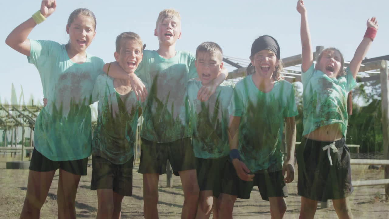 Celebrating outdoors, group of children in matching muddy sports outfits with animation