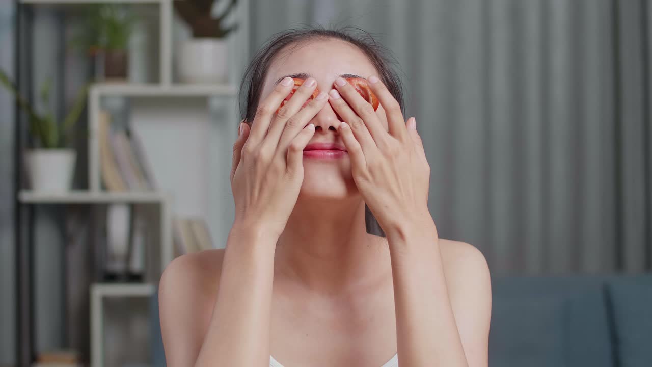 mujer aplicando rebanadas de tomate en los ojos para el cuidado de la piel