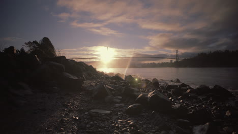 sunrise on rocky beach with bridge in background