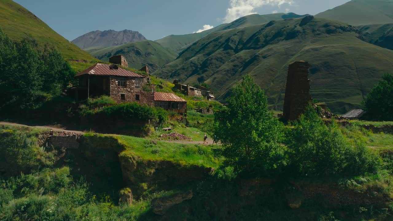 Escursionisti camminano lungo le rovine di una fortezza nella Valle di Truso, Georgia, con montagne imponenti sullo sfondo, creando una scena di avventura alpina drammatica e suggestiva.