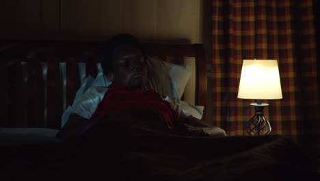 pensive young black man in bed thinking - insomnia