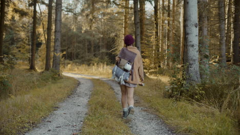 mujer con mochila caminando por el camino en el bosque