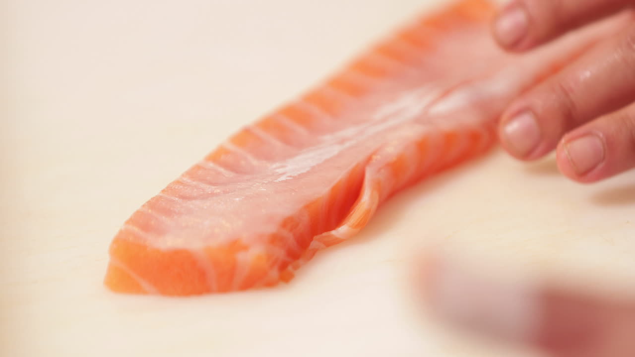 cortar carne de salmón con un cuchillo afilado - preparación de sushi - cerrar