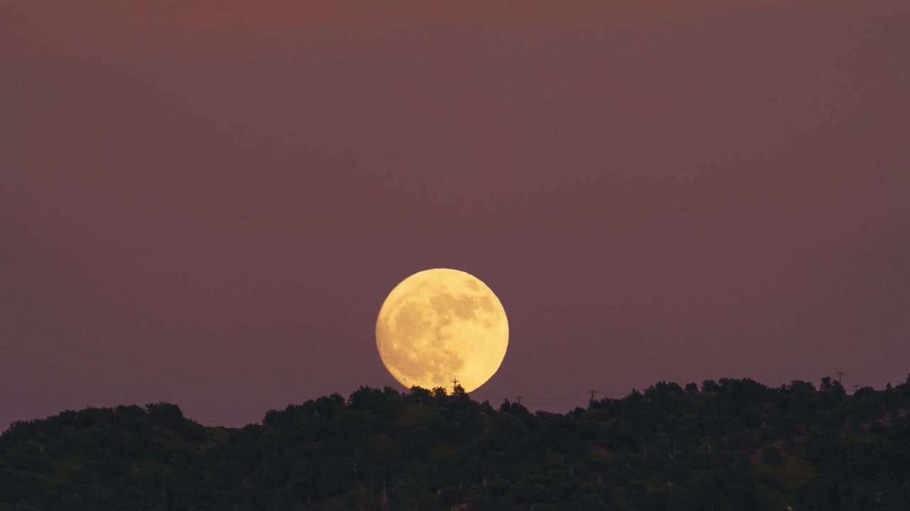 Timelapse da lua cheia nascendo sobre uma crista de montanha ao pôr do sol, filmado do Lago Arrowhead, olhando em direção à Floresta Nacional de San Bernardino, Califórnia.