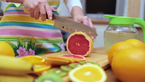 Las-Manos-De-Las-Mujeres-Amas-De-Casa-Cortan-Con-Un-Cuchillo-Pomelo-Fresco-En-La-Tabla-De-Cortar-De-La-Mesa-De-La-Cocina.