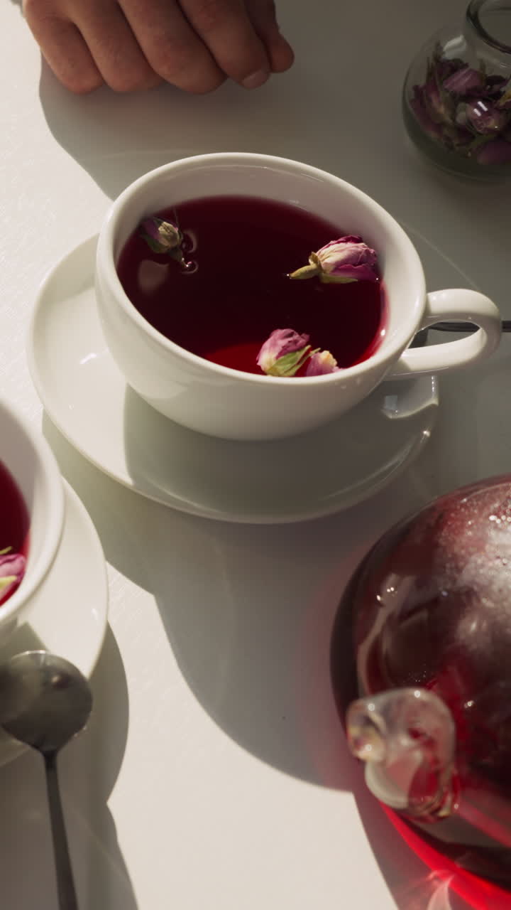 la gente bebe té con brotes de rosas en tazas de primer plano. la pareja disfruta de un desayuno romántico bebiendo té con flores en casa por la mañana. atmosfera de cita perfecta