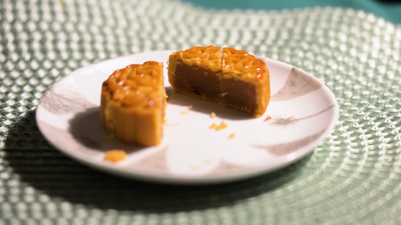This shot shows a cut Chinese mooncake on a plate. It's a traditional bakery product for the Mid-Autumn Festival, a cultural holiday pastry with a detailed pattern