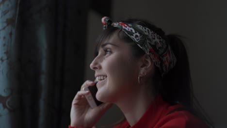 a caucasian woman at home in a red jumper speaking on her mobile phone smiling