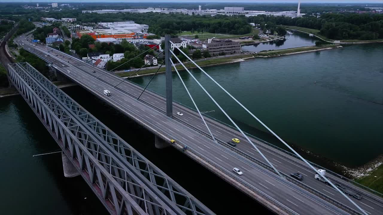 High above Aerial footage of a beautiful Bridge next to a railroad construction spanning over a river with industry areas in the background
