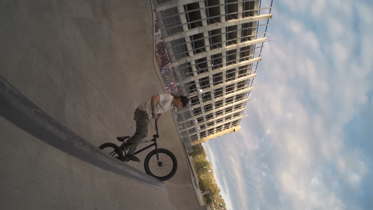 BMX rider tuck no hander huge air in skatepark bowl over spine in extreme slow motion, fisheye lens push in 800 fps