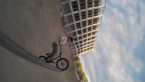 BMX-Fahrer-Macht-Einen-Tuck-No-Hander-Mit-Großem-Air-In-Einer-Skatepark-Bowl-über-Der-Spine-In-Extremer-Zeitlupe,-Fisheye-Objektiv-Push-Mit-800 fps