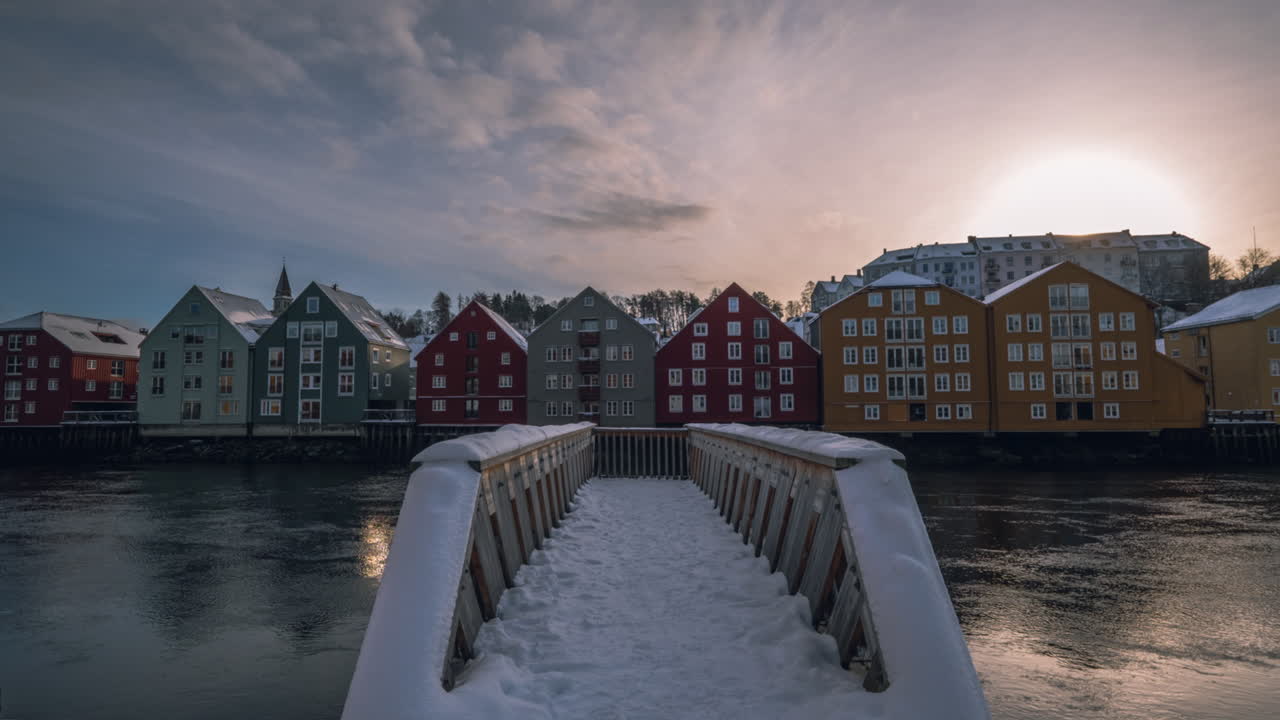 Ponte della Città Vecchia sul fiume Nidelva con passerella coperta di neve al tramonto a Trondheim, Norvegia