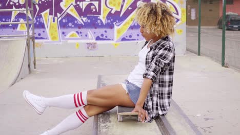 Trendy-young-woman-sitting-on-a-skateboard