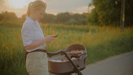 woman using smartphone while walking with baby stroller