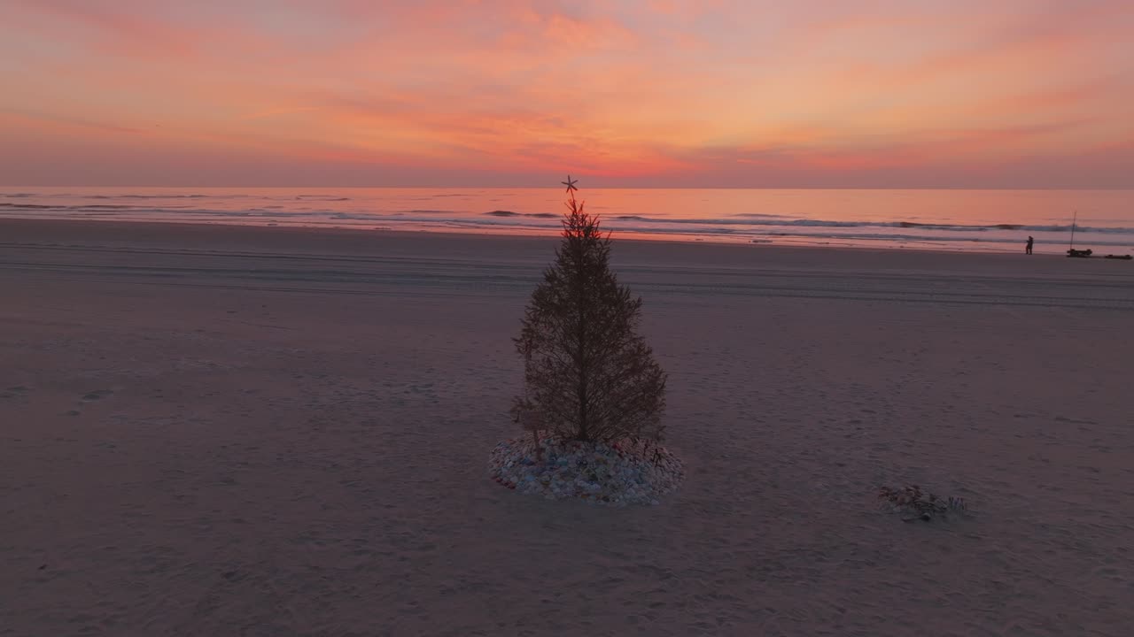 árbol de navidad en la playa con un hermoso amanecer detrás de él