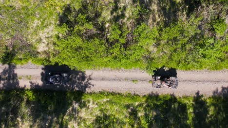 people on 4x4 quadbikes taking off on dirt trail in outdoors, top down