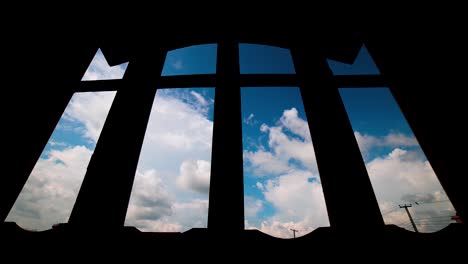 Low-Angle-View-of-White-Cotton-Clouds-Taking-Over-By-Dark-Monsoon-Clouds-Time-Lapse-Against-Silhouetted-Window-Frame