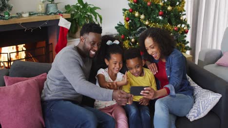 Lächelnde-Afroamerikanische-Familie,-Die-Einen-Videoanruf-Führt-Und-Gestikuliert,-Weihnachtsdekorationen-Im-Hintergrund