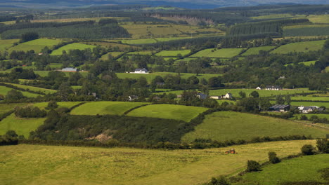 lapso de tiempo del paisaje agrícola rural en un día soleado de verano con tractor corriendo por el campo en irlanda