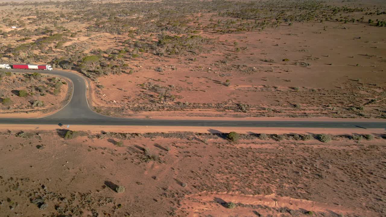 Aerial view of trucks parking on 90mile straight road, australia on a sunny, desert outback - pan drone shot