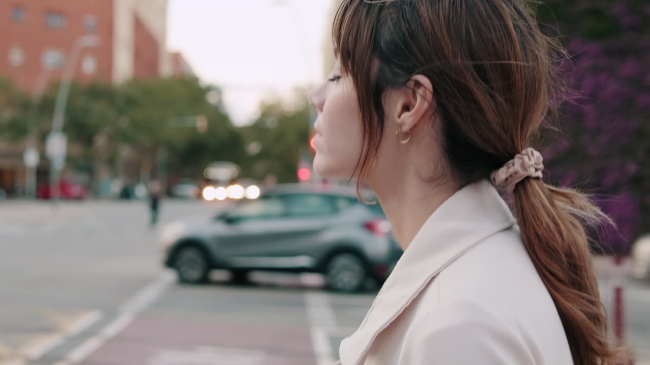 街の通りで物思いにふけりながら立つ若い女性