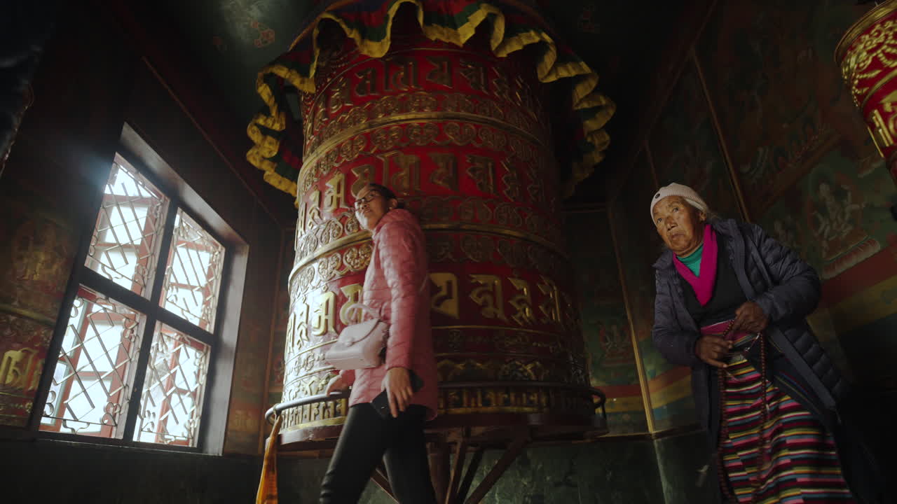 Prayer wheels and people in a Buddhist temple