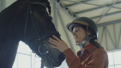 woman petting a horse in a stable