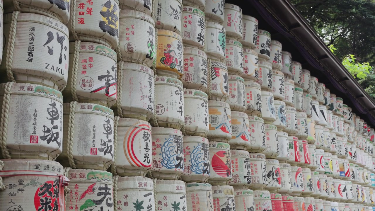 Video gerak lambat yang bergerak menyusuri tong sake berwarna-warni dan indah di Kuil Meiji Jingu pada siang hari di Taman Yoyogi, Tokyo.
