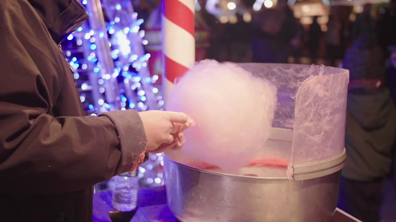 una mujer haciendo hilo de caramelo rosa en cámara lenta en el mercado navideño de montpellier, francia.