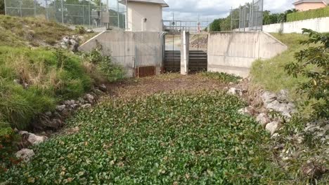 Drone-shot-low-to-the-water-slowly-ascending-over-a-water-treatment-area-on-a-canal