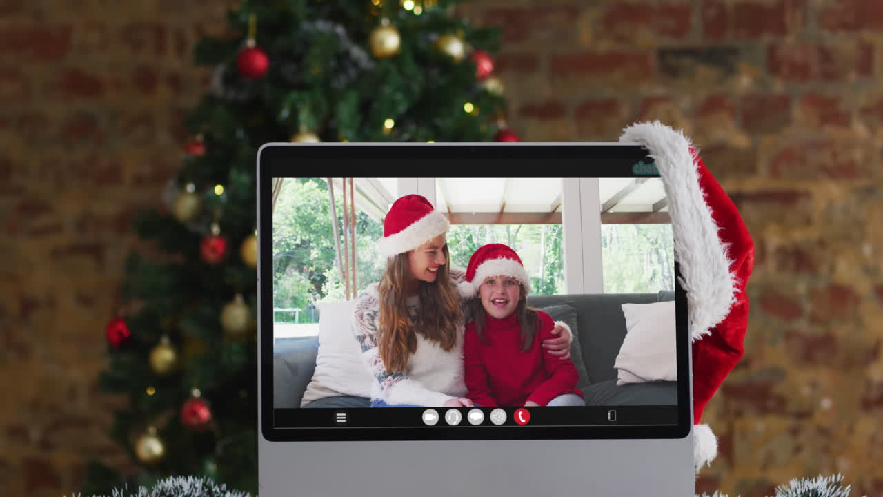madre y hija felices con sombreros de santa en una videollamada en la computadora, con decoraciones de navidad