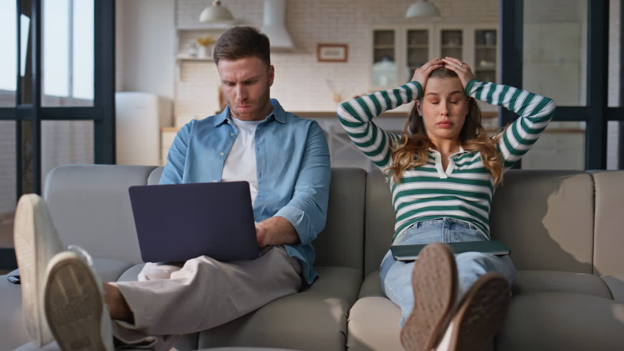 Talking pair working laptops at living room interior. Tired lady closing gadget