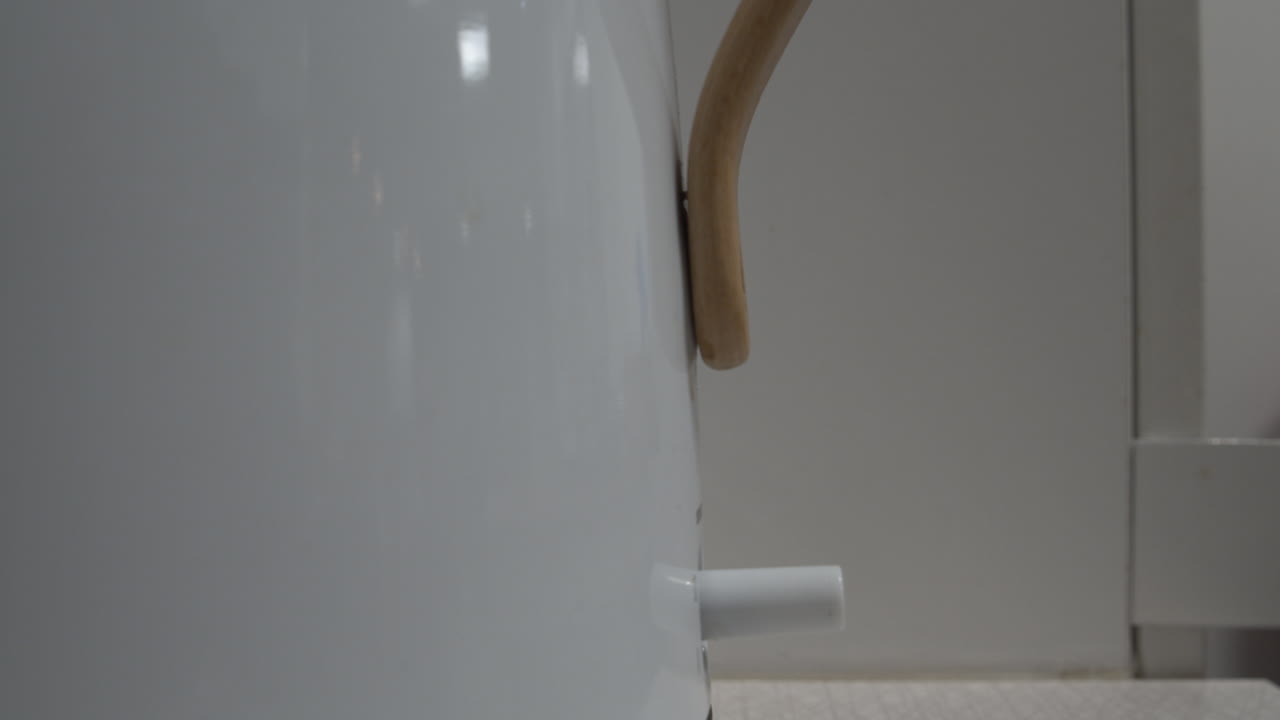 Closeup shot of a white kettle boiling showing the switch clicking off at boiling point